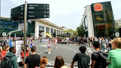 Pista exterior del 3x3 Westfield Glòries plena de públic, amb el Burger King i el Carrefour de la plaça de les Glòries al fons
