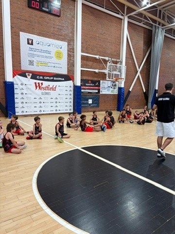 Infants de la Cistella Petita asseguts escoltant l'entrenador